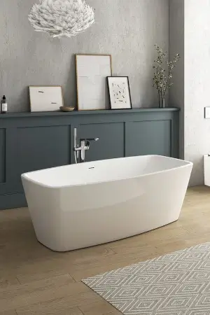A white bath sits on a wooden floor in front of dark gray panelling